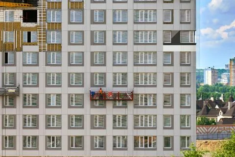 Worker in a construction cradle on the wall of a building under construction 写真素材