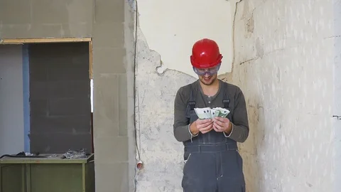 The worker in a construction with helmet counts money euro against the Видео 100142559