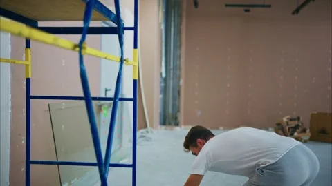 A Worker in a Construction Setting Adjusting a Scaffold, Preparing for Painting Stock Footage 316056080