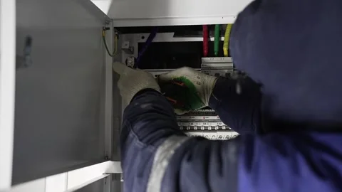 Worker at a construction site assembles an Electrical panel Stock Footage 257014935