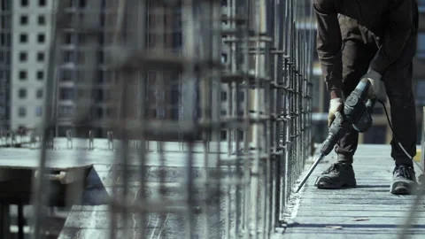 Worker at a construction site breaks concrete with a jackhammer Video stock 255649360