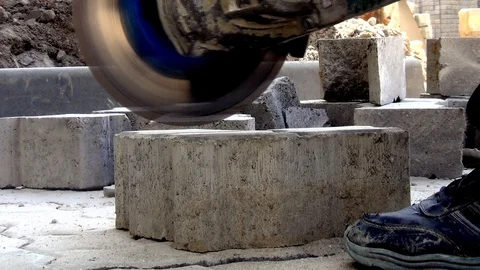 A worker at a construction site cuts off a paving slab with an angle grinder. Du Stock Footage 112981012