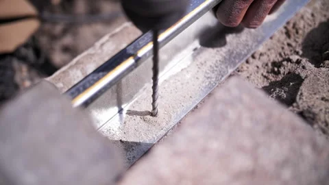 A worker at a construction site drills a hole Видео 241497136