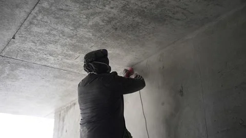 Worker at a construction site grinds concrete walls Stock Footage 254511774