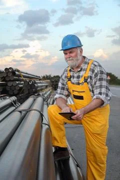 Worker at construction site with heap of pipes Stock Photos