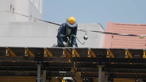 Worker on construction site installs materials on a building under bright sun Stock Footage 338245525