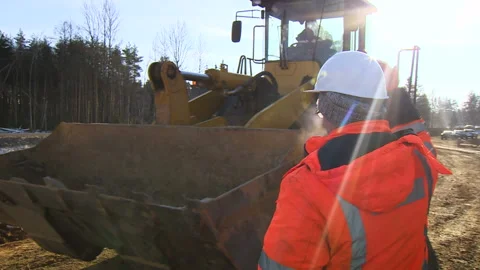 Worker at the construction site next to the excavator. Excavator at the Video stock 94486517