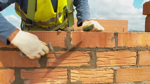 A worker on a construction site pours cement mortar between the bricks Stock Footage 157320436