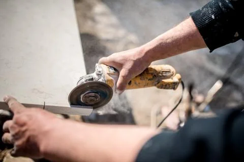 Worker at construction site using grinder for cutting slate Stock Photos