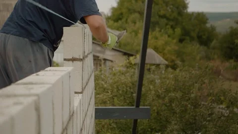 Worker constructs a concrete brick wall at a residential building site Stock Footage 324669192