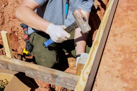 Worker constructs a wooden frame for a foundation in a construction area on a Stock Photos