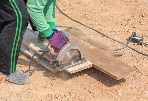 Worker contractor using circular saw to cut formwork boards Stock Photos