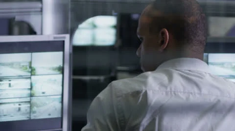 Worker in a control room is watching the screens and making a phone call Stock Footage 24984379