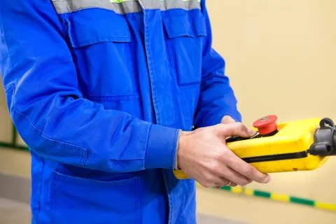 The worker controls the crane in warehouse from the remote. Foto stock