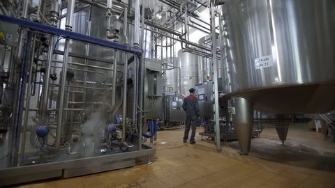 Worker controls equipment operation at dairy factory. Huge cisterns for storing Vídeo Stock 106125047