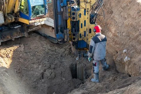 A worker controls the extraction of Larssen sheet piling from the ground Fotos Stock