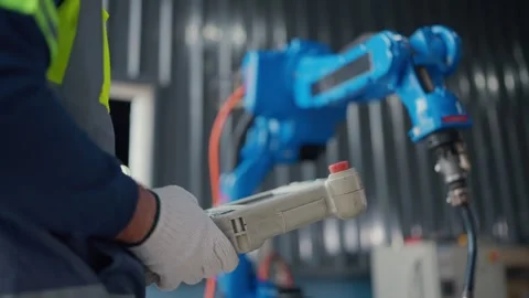 Worker controls robotic arm in factory setting Video stock 341314506
