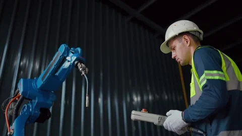 Worker controls robotic arm with handheld device 库存影片 344919623