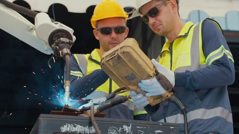 Worker controls robotic arm with handheld device Stockbeeldmateriaal 344920916