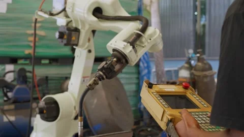 Worker controls robotic arm with handheld device 動画素材 344921016