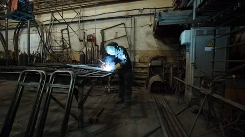 A worker cooks metal on a welding machine in production. a worker with a welding Stock Footage 178852991
