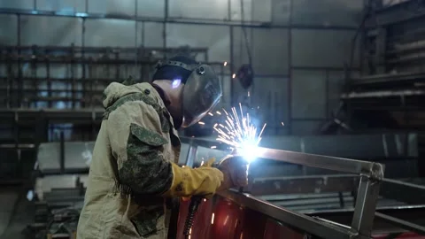 A worker cooks metal on a welding machine in production. a worker with a welding Stock Footage 178853791