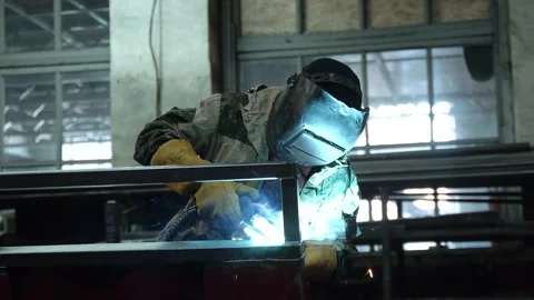 A worker cooks metal on a welding machine in production. a worker with a welding Stock Footage 178854036