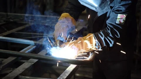 A worker cooks metal on a welding machine in production. a worker with a welding Stock Footage 178854326