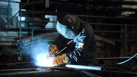 A worker cooks metal on a welding machine in production. a worker with a welding Stock Footage 178854339