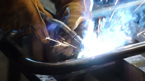 A worker cooks metal on a welding machine in production. a worker with a welding Stock Footage 178854622