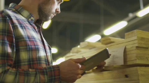 Worker counts wood stock using a tablet computer at a lumber factory warehouse Stock Footage 62545551