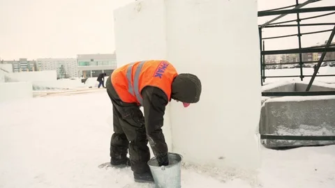 Worker covers the joints of ice panels with wet snow Stock Footage 106692400
