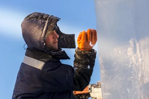 Worker covers the joints of ice panels with wet snow 스톡 사진