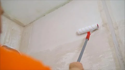 A worker covers the wall with plaster. Worker and roller. Male hand painting Stock Photos