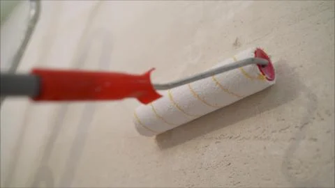 A worker covers the wall with plaster. Worker and roller. Male hand painting Stock Photos