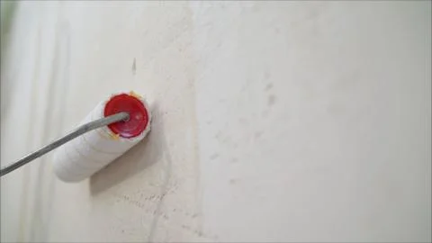A worker covers the wall with plaster. Worker and roller. Male hand painting 스톡 사진