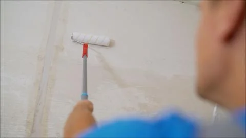 A worker covers the wall with plaster. Worker and roller. Male hand painting  스톡 사진