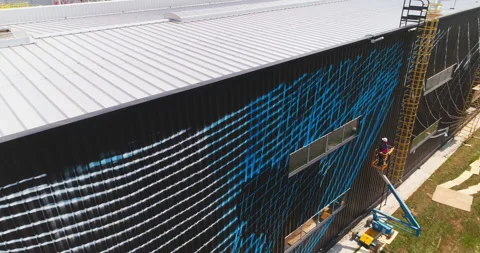 Worker in crane cradle inspects pattern on factory facade Stock Footage 221426241