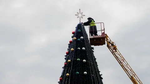 Worker on the crane install and decorate the Christmas tree. Video stock 83676569