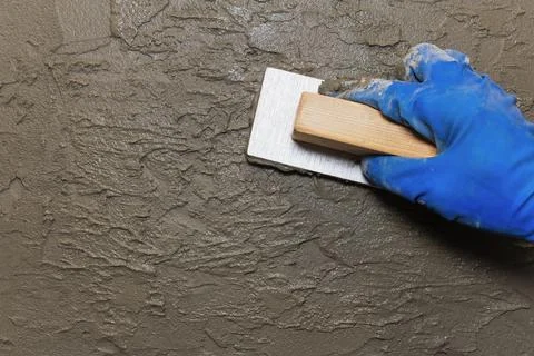 Worker creates unevenness in the plaster to imitate antiquity using a float. Stock Photos