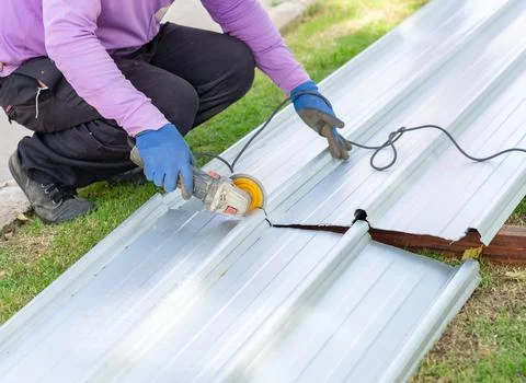 The worker is crouched on the grass and pavement next to the sheet. Stock Photos