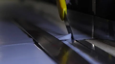 Worker cut fabric with utility knife on metal surface with slots for even cut. Stock Footage 313815355