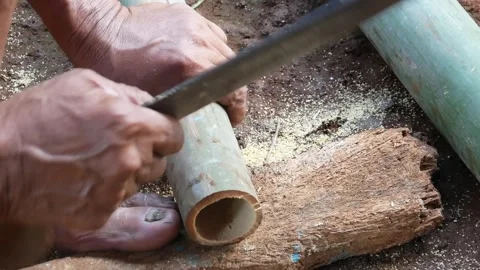 A worker cuts bamboo using a machete Stock Footage 310125843