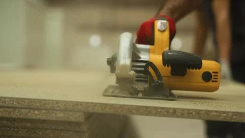 A worker cuts chipboard with an electric hand saw. Stock Footage 247702772