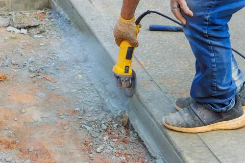 Worker cuts concrete with grinder during construction at worksite Stock Photos