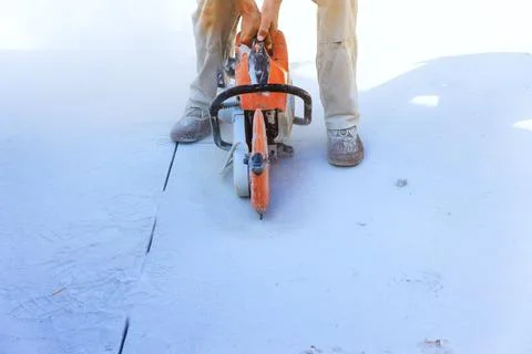 Worker cuts concrete with saw at construction site Stock Photos