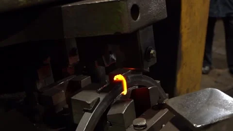 A worker cuts off excess pieces of hot metal on an anvil under a mechanical pres Video stock 143311235