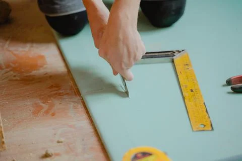 A worker cuts a flat sheet on a wall with a construction knife, construction  Stock-Fotos