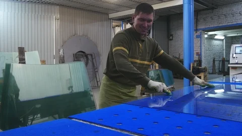 A worker cuts glass on a blue table and sets on the counter.Float glass. 스톡 동영상 122217489