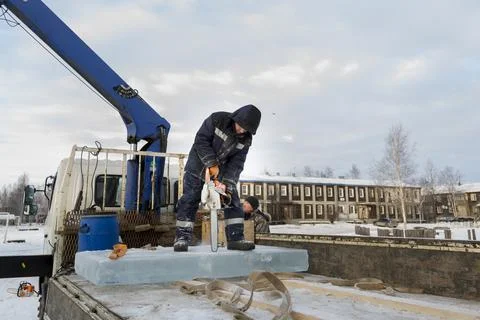 A worker cuts a hole in the ice panel with a chainsaw 스톡 사진
